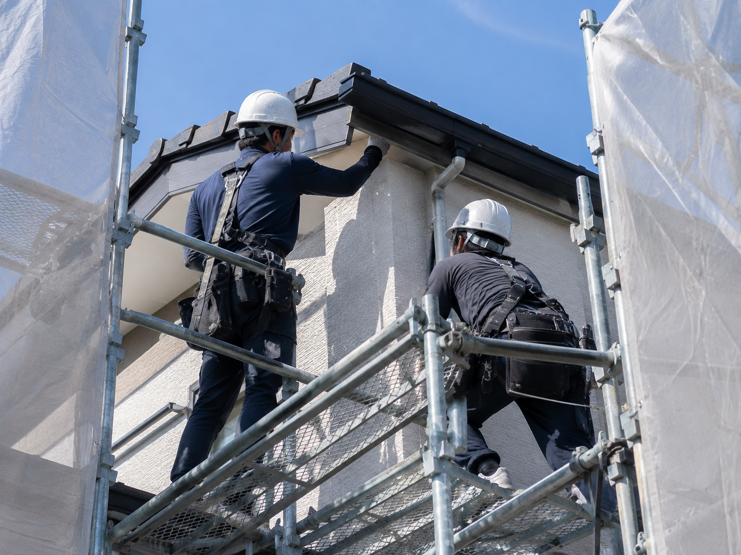 足場の上で建物の状態を確認する職人